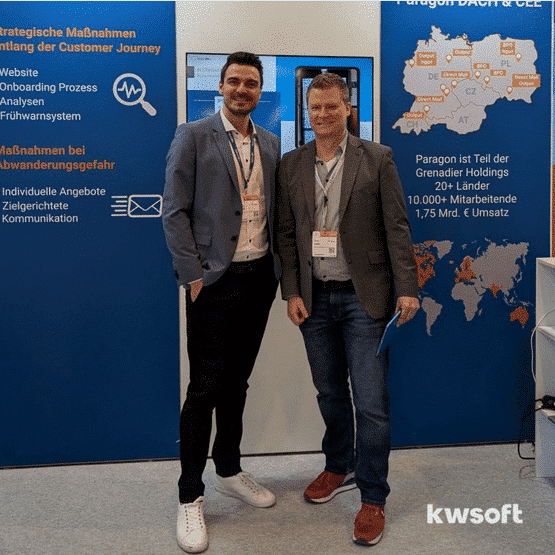 Marco Leven und Philip Moser stehen vor dem Paragon-Schild auf der E-world 2025.