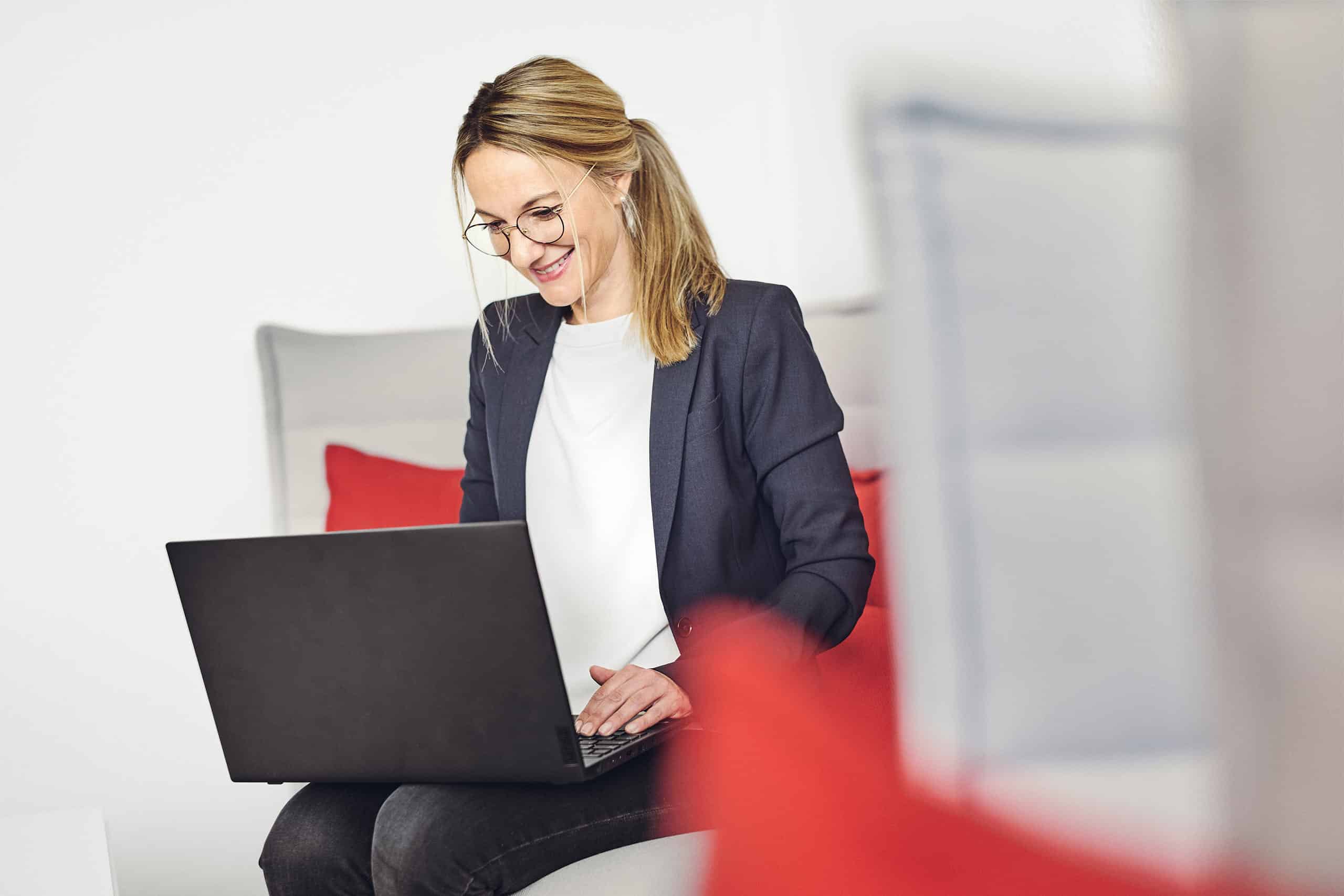 Celine Spitz arbeitet an ihrem Laptop auf dem Sofa in der kwsoft-Lounge.