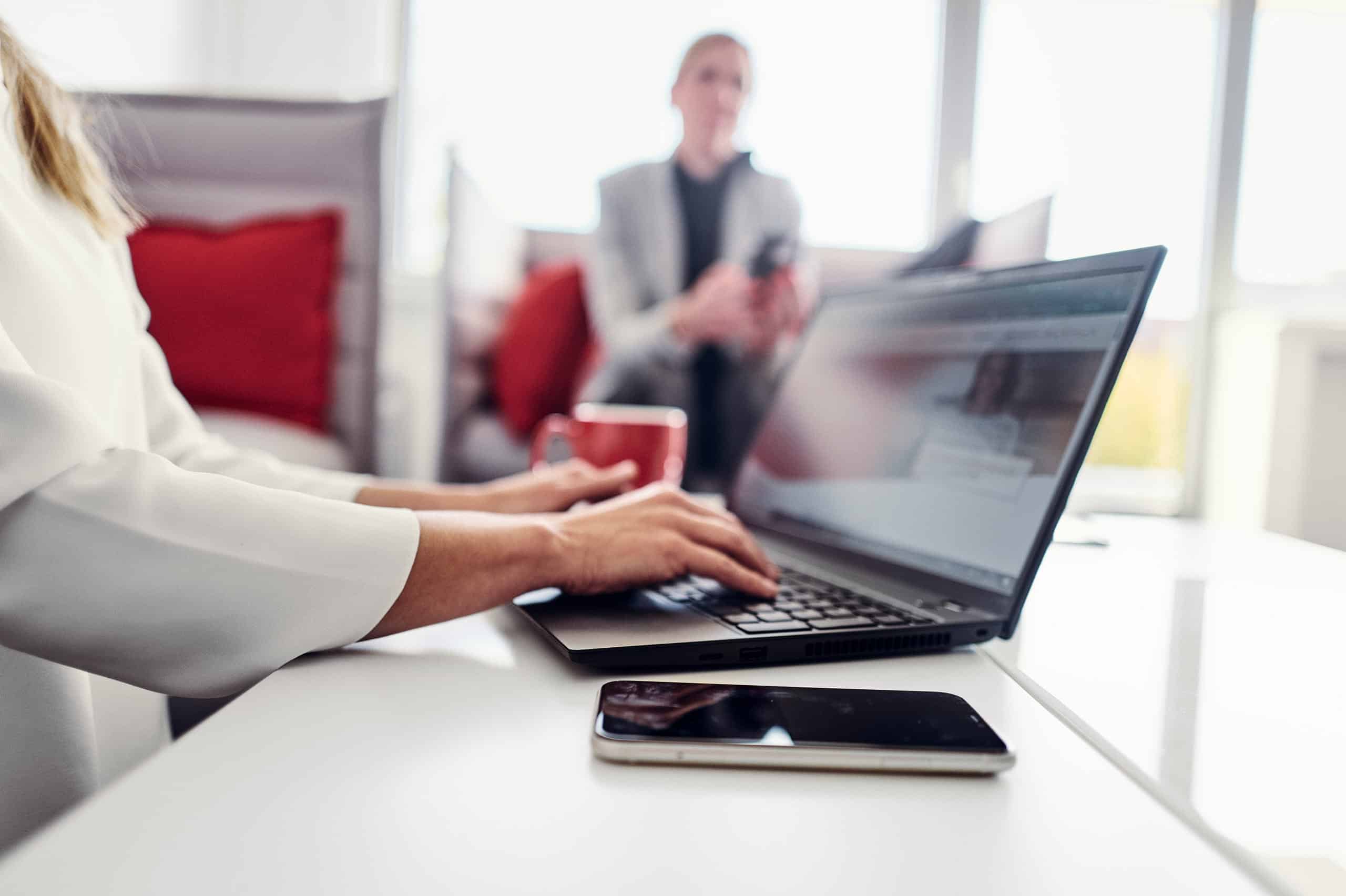 Eine Person sitzt auf dem Sofa in der kwsoft® Lounge besucht auf ihrem Laptop die kwsoft® Website.