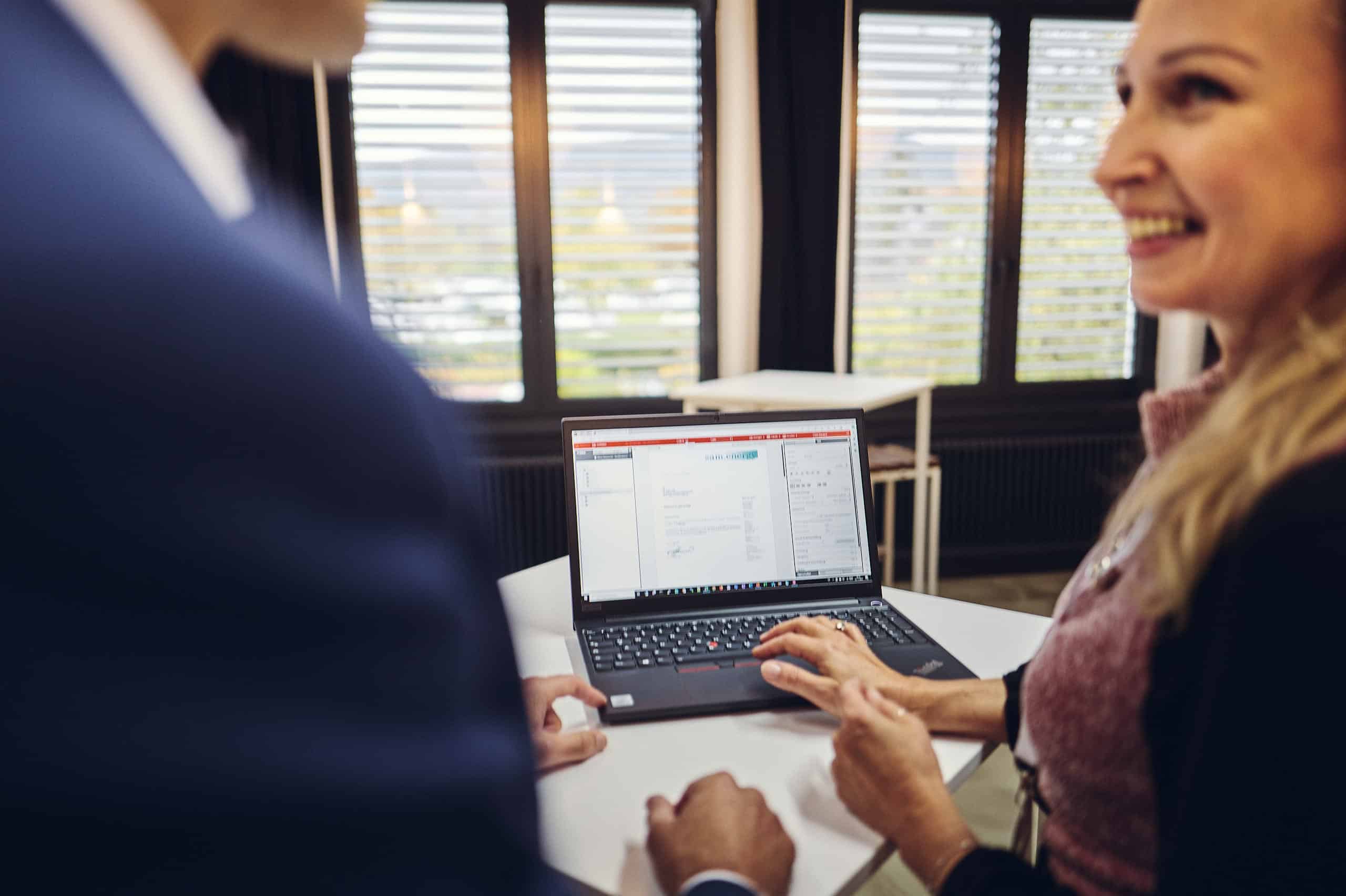 Zwei Personen schauen sich einen Laptop an und unterhalten sich darüber.