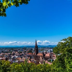 Ein Foto von Freiburg im Sommer von oben. Man kann das Freiburger Münster klar erkennen.