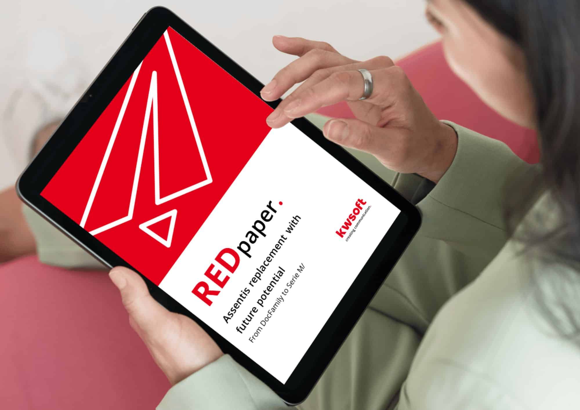 Das Bild zeigt ein Tablet, das von jemandem gehalten wird und auf dem das Cover des REDpaper „Assentis Replacement” zu sehen ist.
