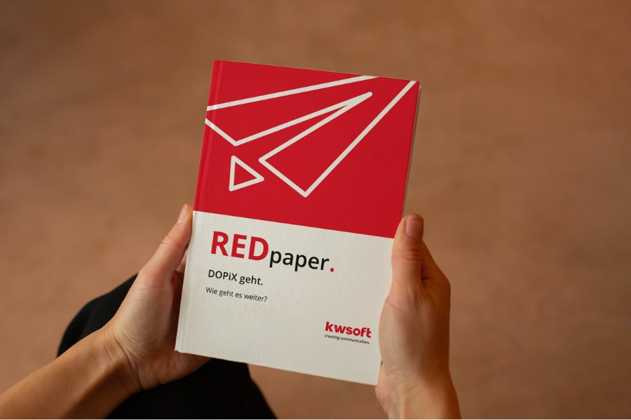 Das Bild zeigt eine Person, die das REDpaper zum Thema „DOPiX”-Ablösung in der Hand hält.
