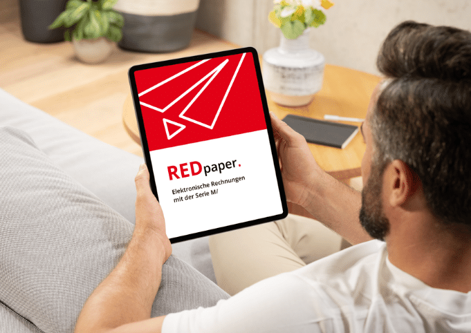 Mann schaut auf Tablet mit Titelbild des kwsoft REDpapers "Elektronische Rechnungen mit der Serie M/"
